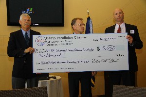 In April, Rick Hancock (r), vice president, business systems, QinetiQ – North America, presents a $5,000 donation to Grundies (l) and Witzel for the chapter's Wounded War Veterans Scholarship.